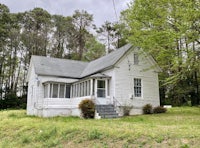 an old white house sitting in the middle of the woods
