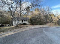 a house with a driveway in the middle of a wooded area