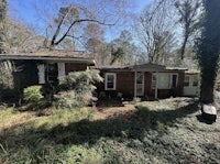 a brick house in the middle of a wooded area